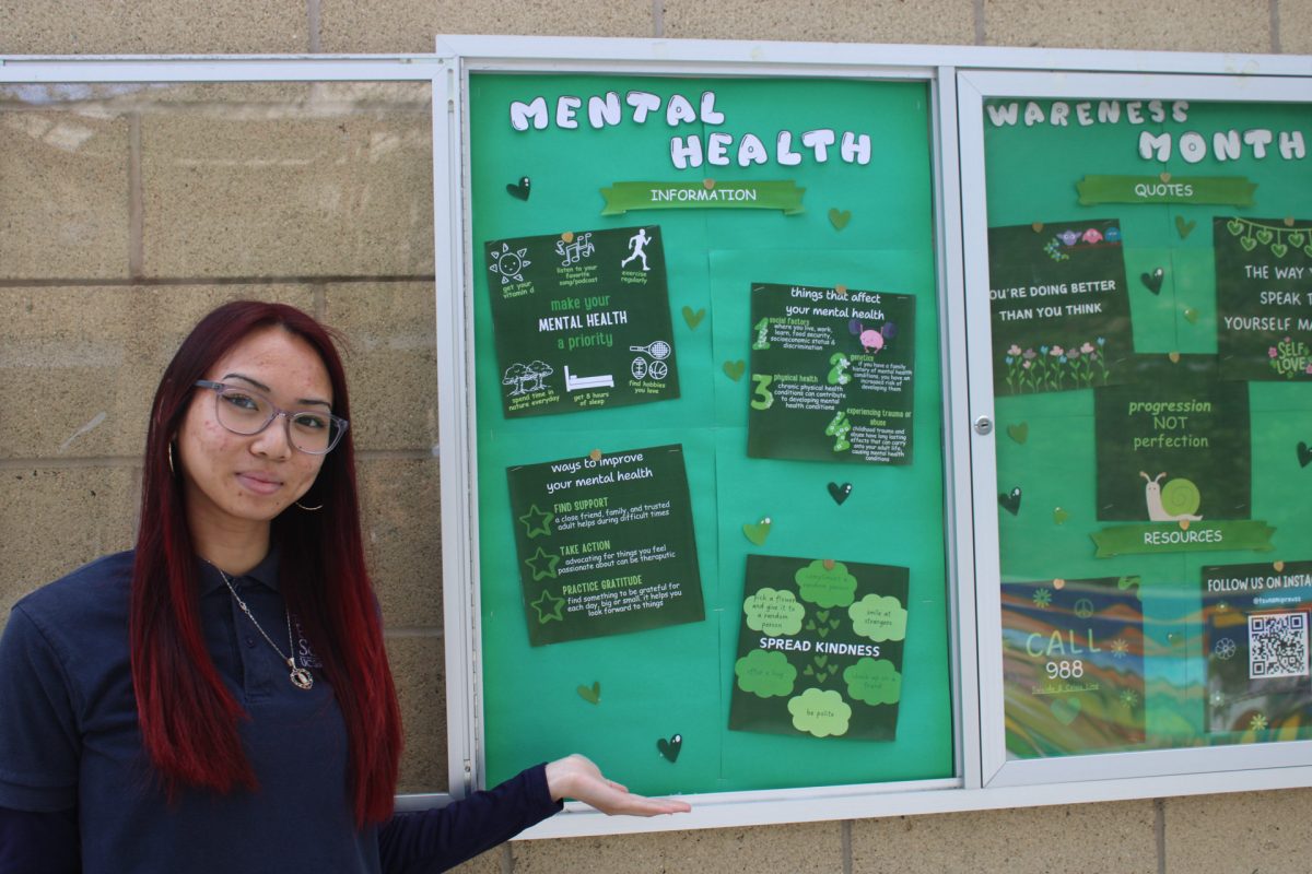 Tracy Trinh (24) updating the mental health themed glass case on campus.