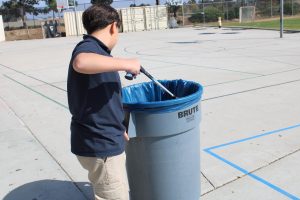 Student picking up trash during lunch due to him being tardy to his classes