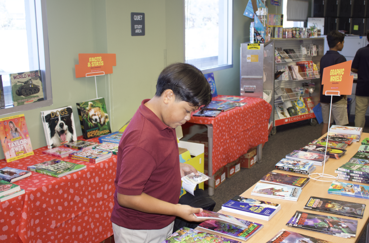 Middle schooler skimming through books while shopping at the Book Fair.